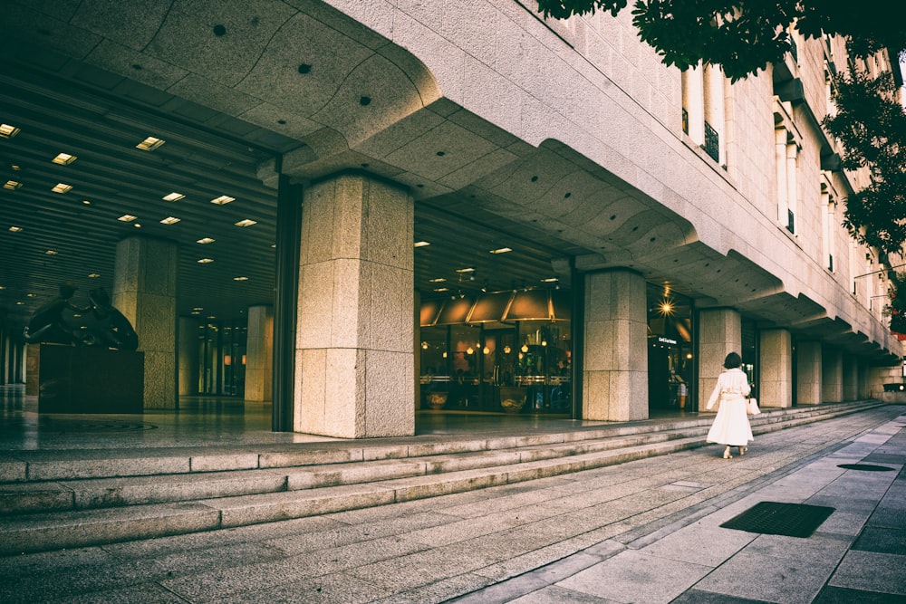 a woman in a white dress is walking down the street