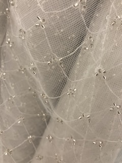Close-up of delicate champagne sheen beads arranged on a mist sage fabric background.