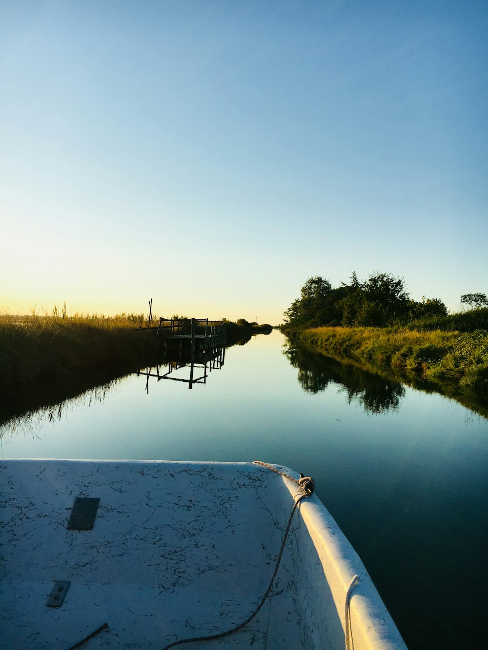 a boat traveling down a river next to a lush green field