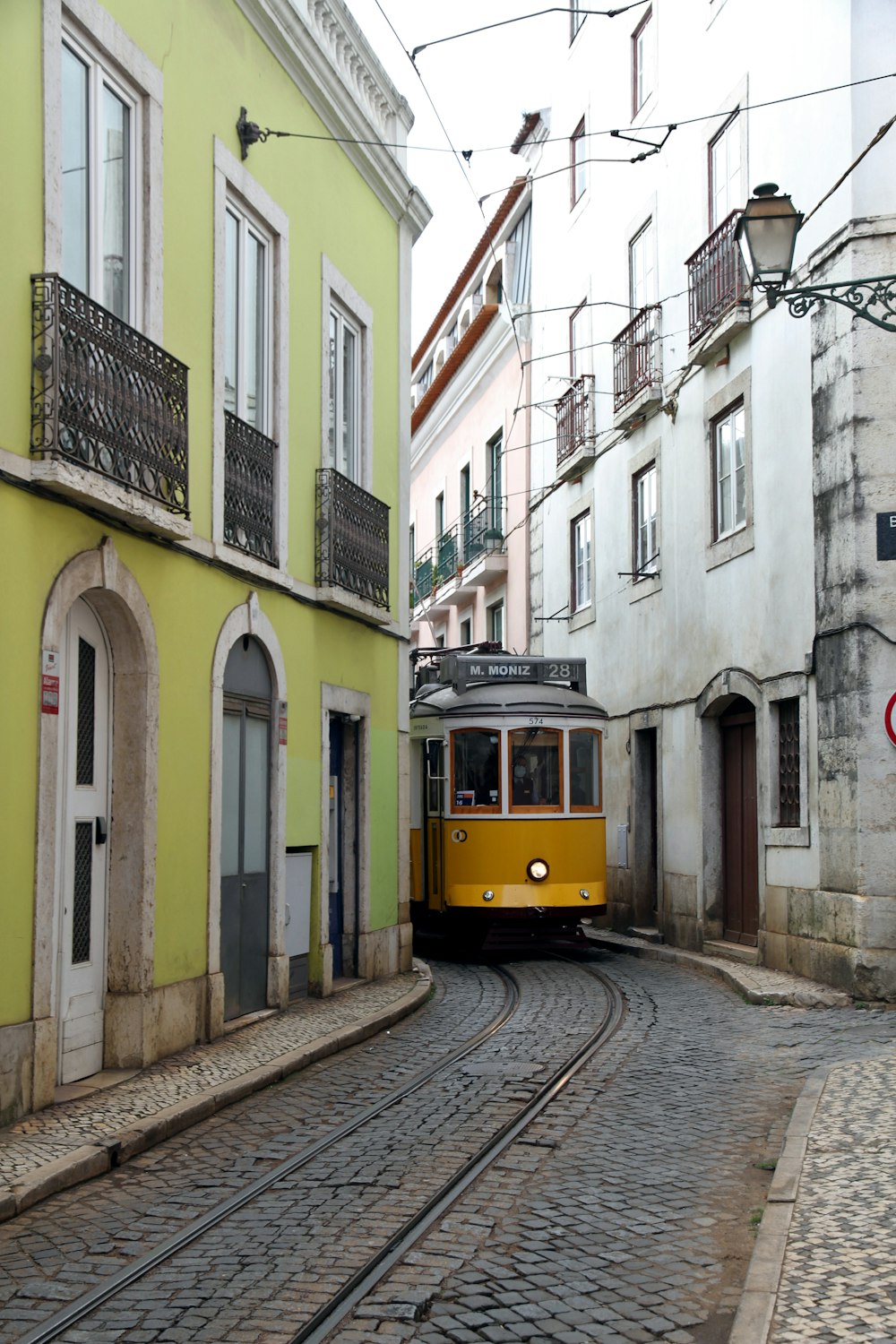 a yellow trolley is going down a cobblestone street