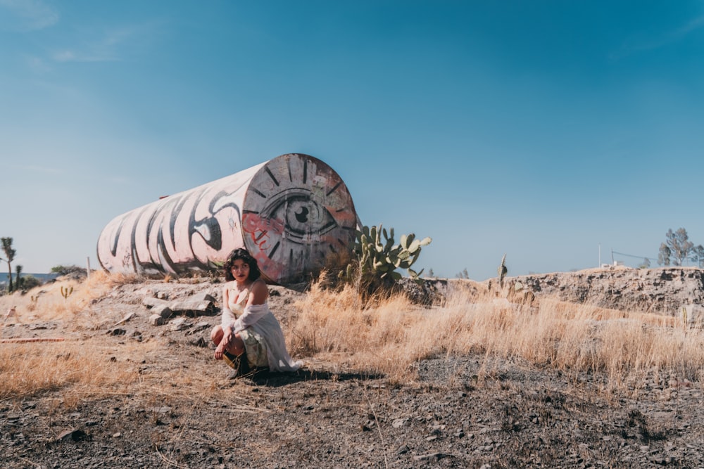 a woman sitting in front of a large piece of art