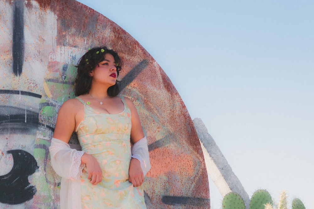 a woman in a dress standing in front of a wall