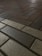 Dark, textured brick pavement arranged in a herringbone pattern, with variations in color from light gray to dark brown.