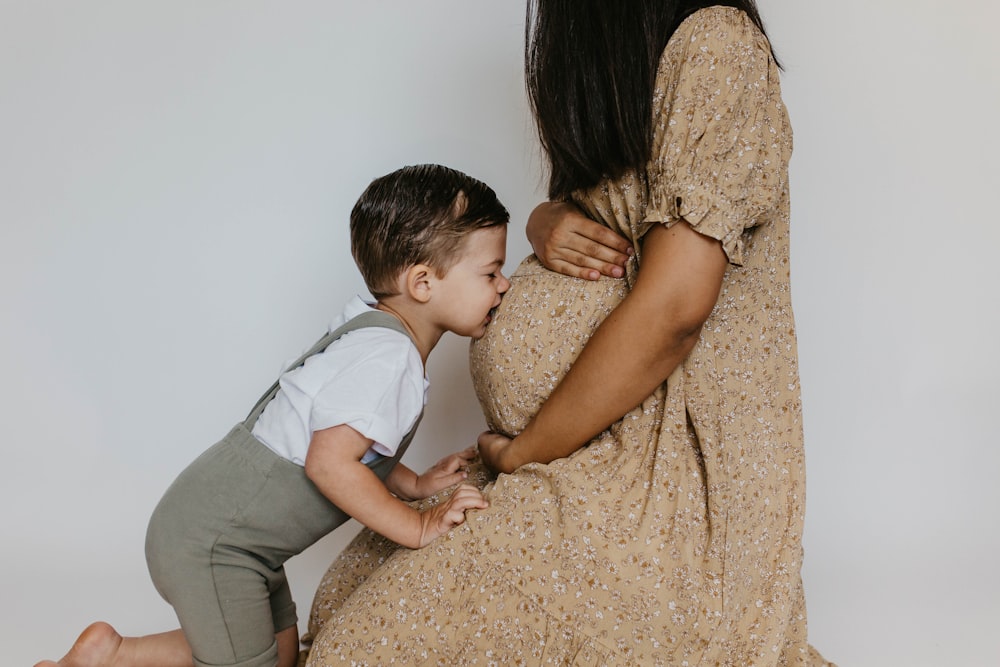 a woman holding a baby boy and kissing him