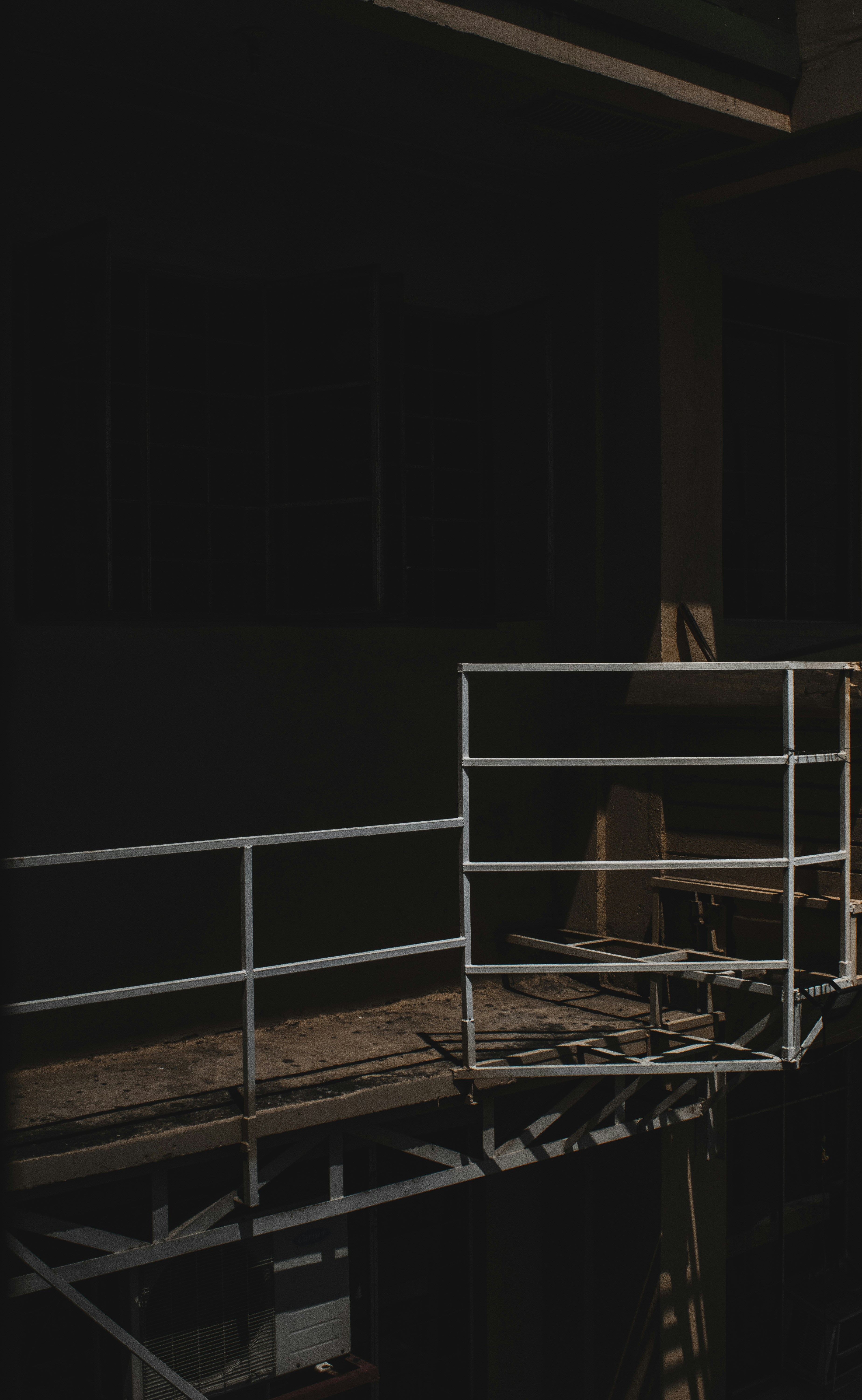 Industrial steel platform walkway in factory, dark metal grating floor, deep shadows, moody industrial lighting