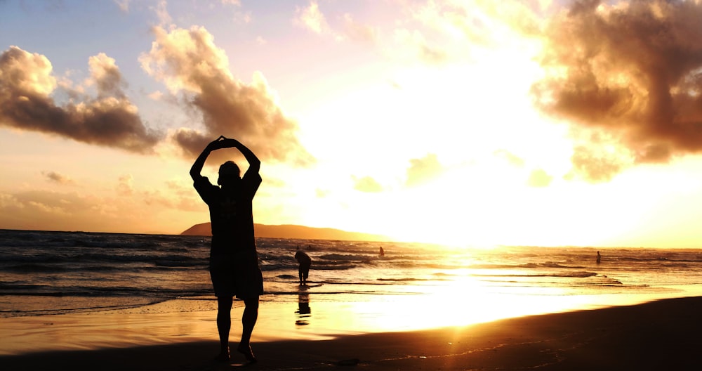 a person standing on a beach with their arms in the air