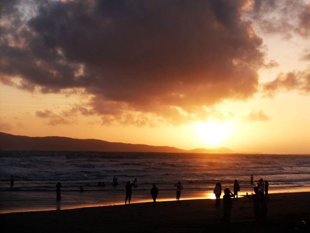 a group of people standing on top of a beach under a cloudy sky