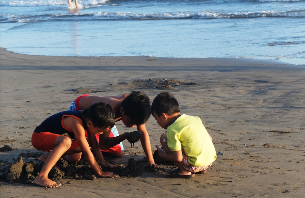 Trois enfants jouant dans le sable à la plage