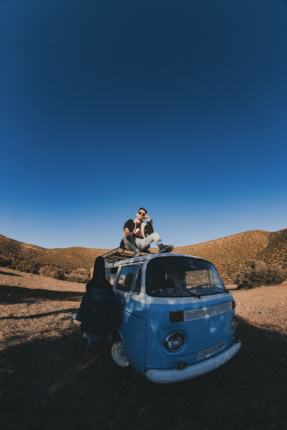 a group of people sitting on top of a blue van