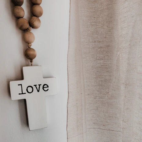 A softly lit studio corner featuring a pastel-hued canvas with a delicate cross and gentle brushstrokes symbolizing faith and peace.