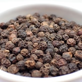 a white bowl filled with lots of black pepper