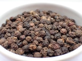 a white bowl filled with lots of black pepper