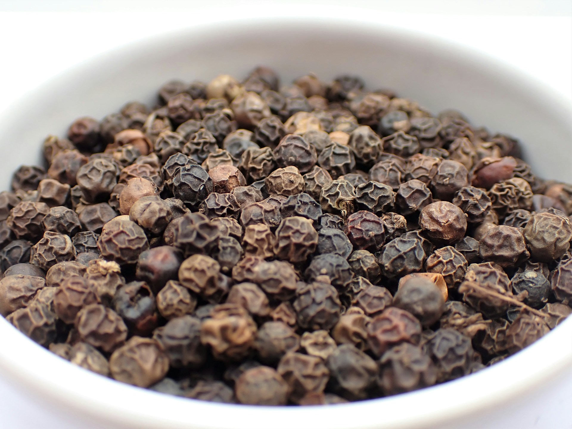 a white bowl filled with lots of black pepper