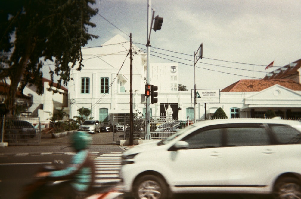 a white car driving down a street next to a traffic light