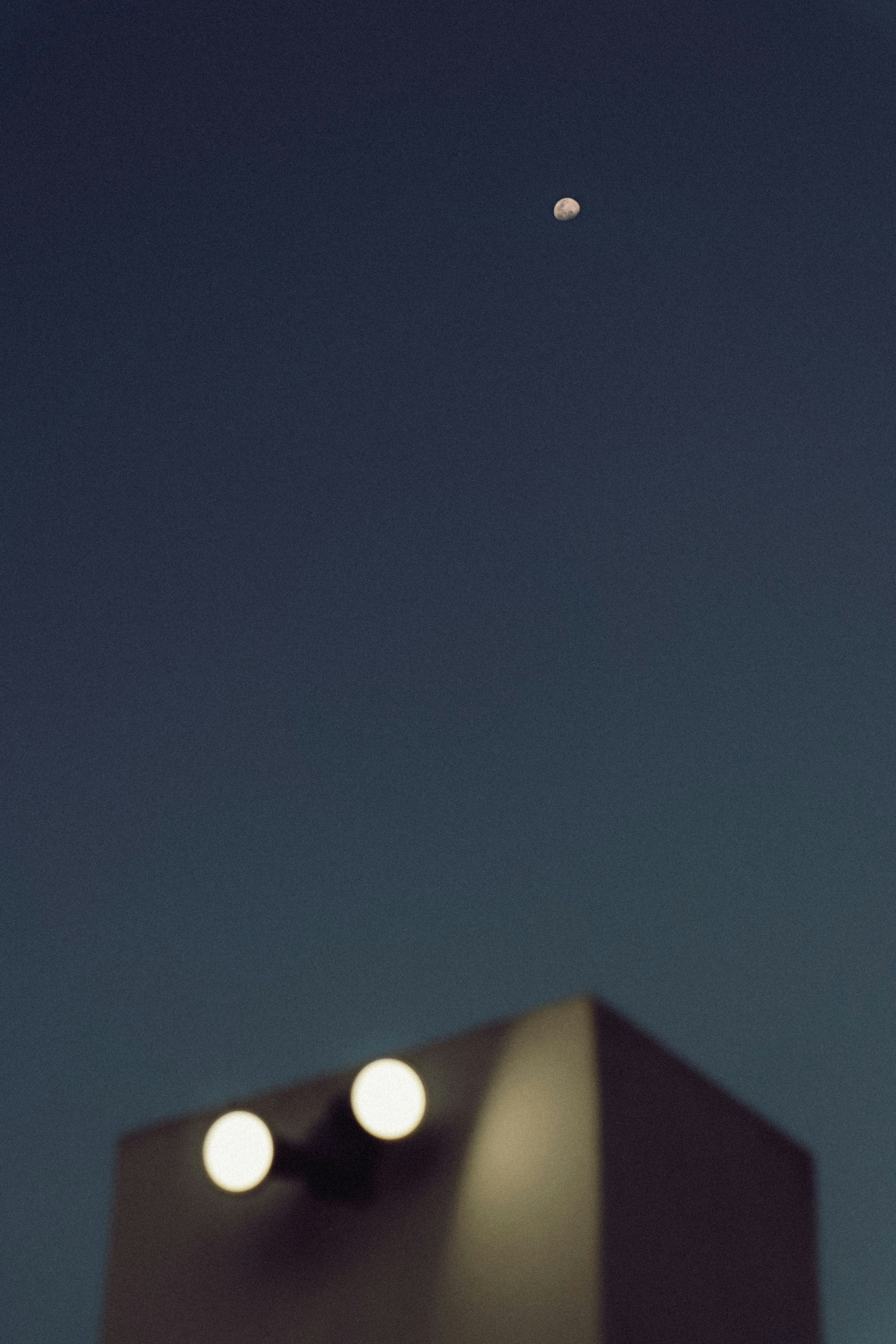 a building with lights on it and a moon in the sky