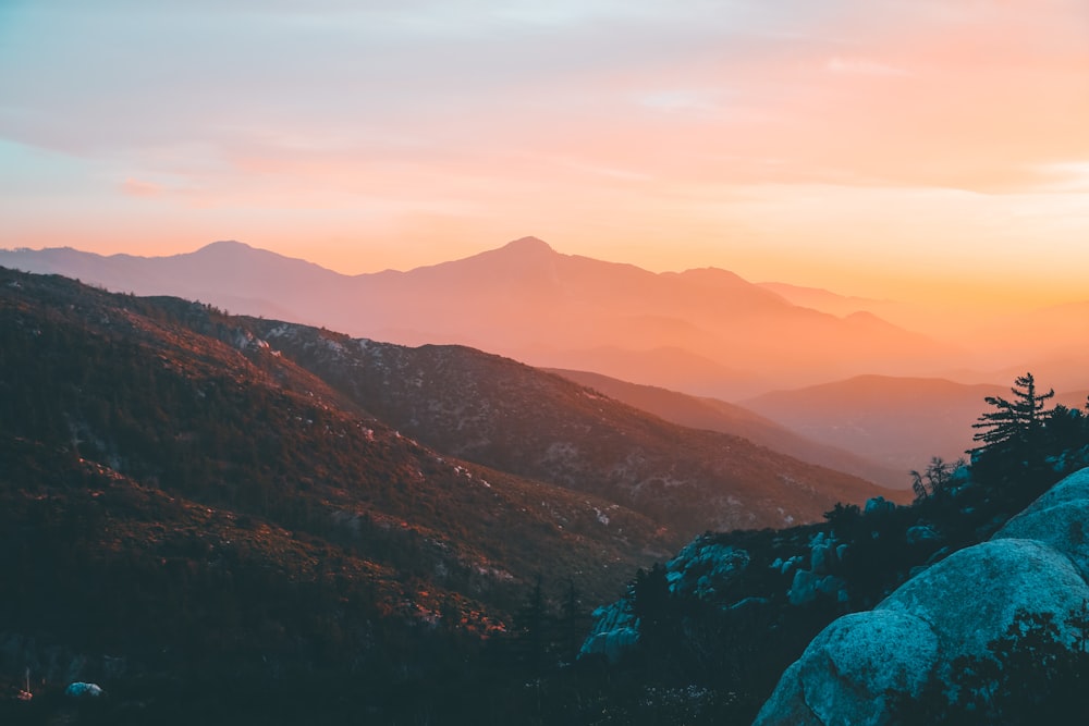 uma pessoa em pé no topo de uma montanha ao pôr do sol