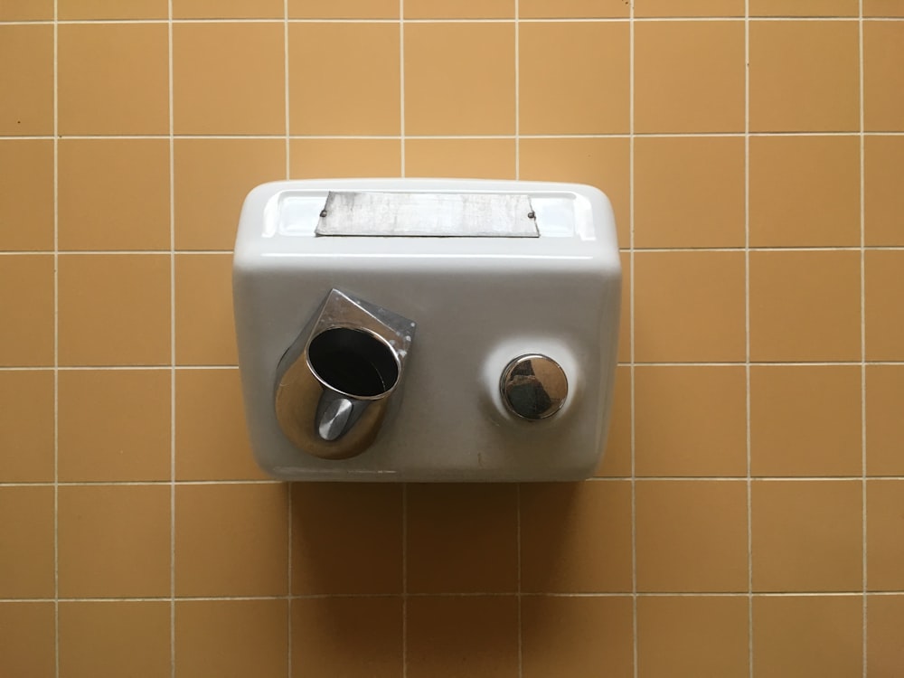 a close up of a wall mounted soap dispenser