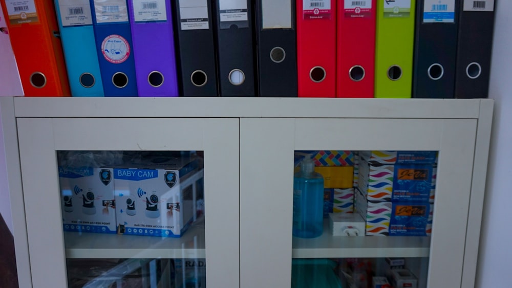 a glass door cabinet with a bunch of folders on top of it