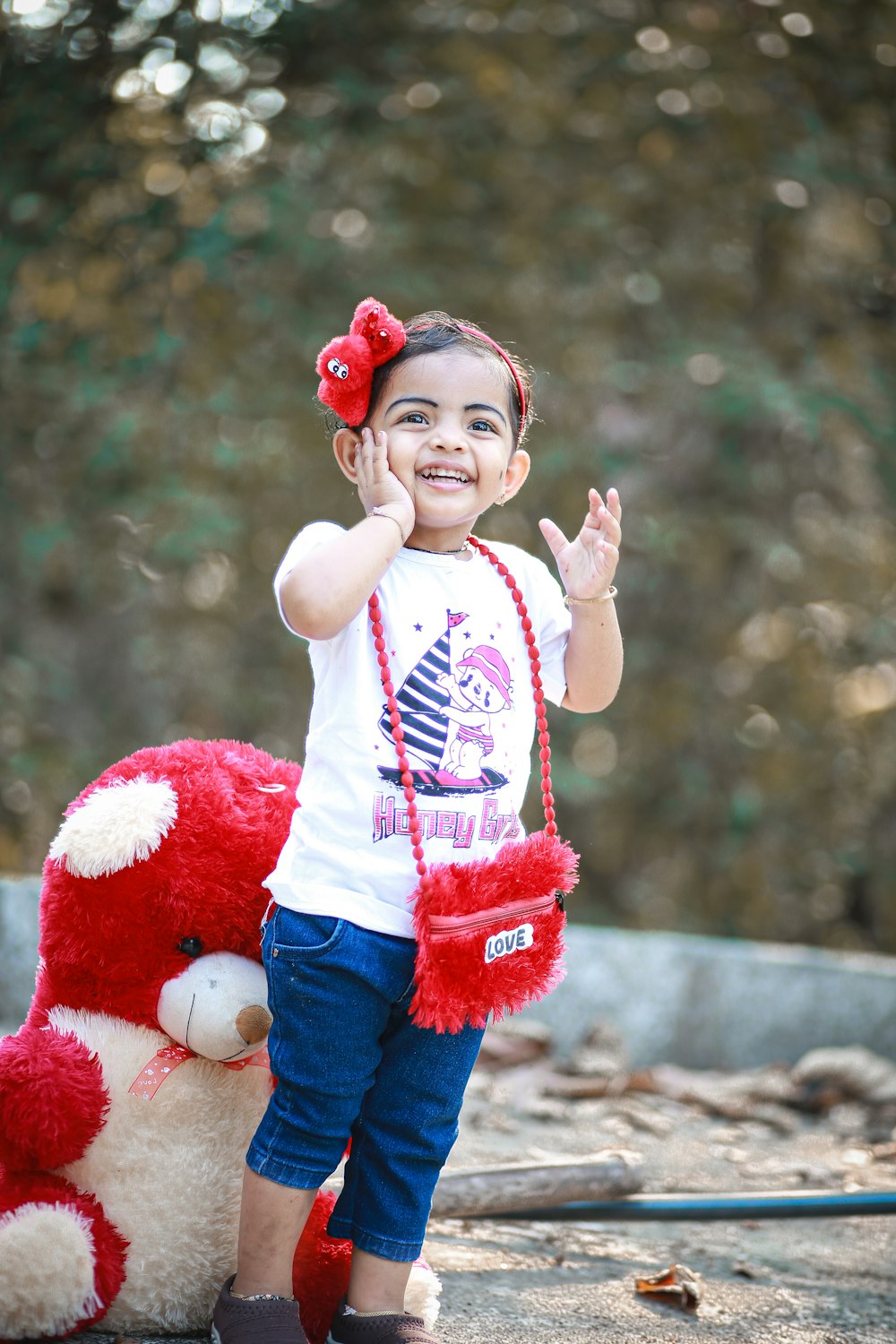 a little girl standing next to a stuffed animal