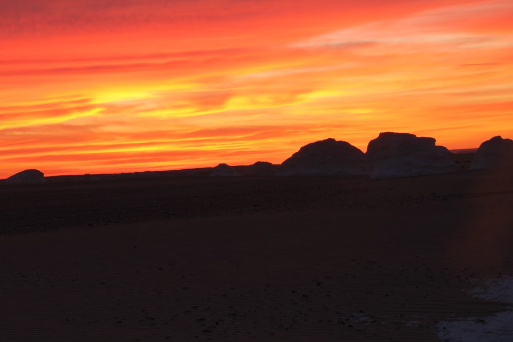 the sun is setting over some rocks on the beach