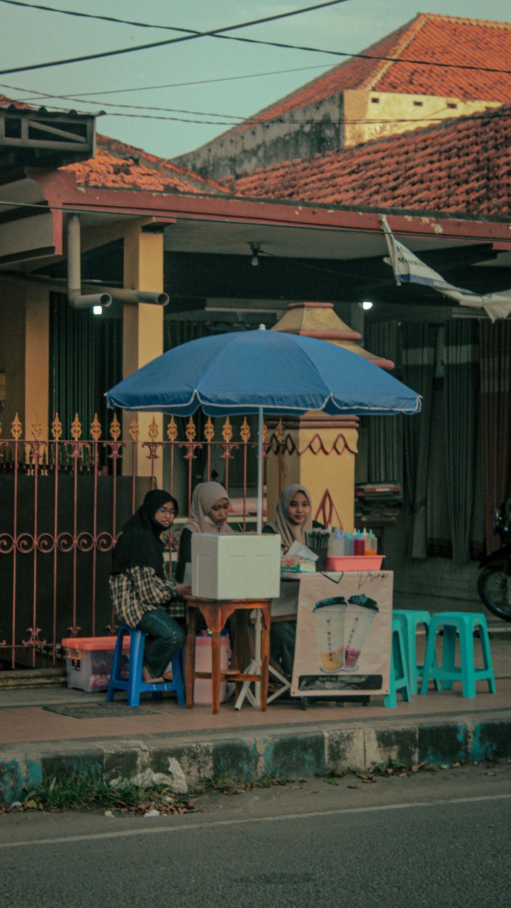 a couple of people sitting at a table under a blue umbrella
