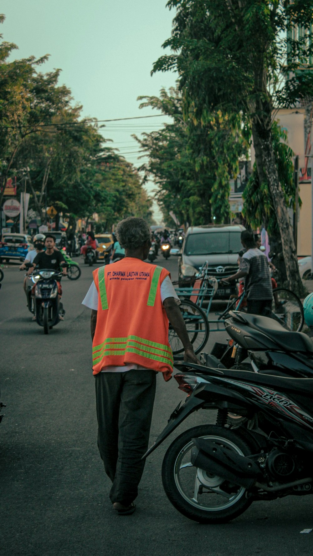 a man walking down a street next to a motorcycle