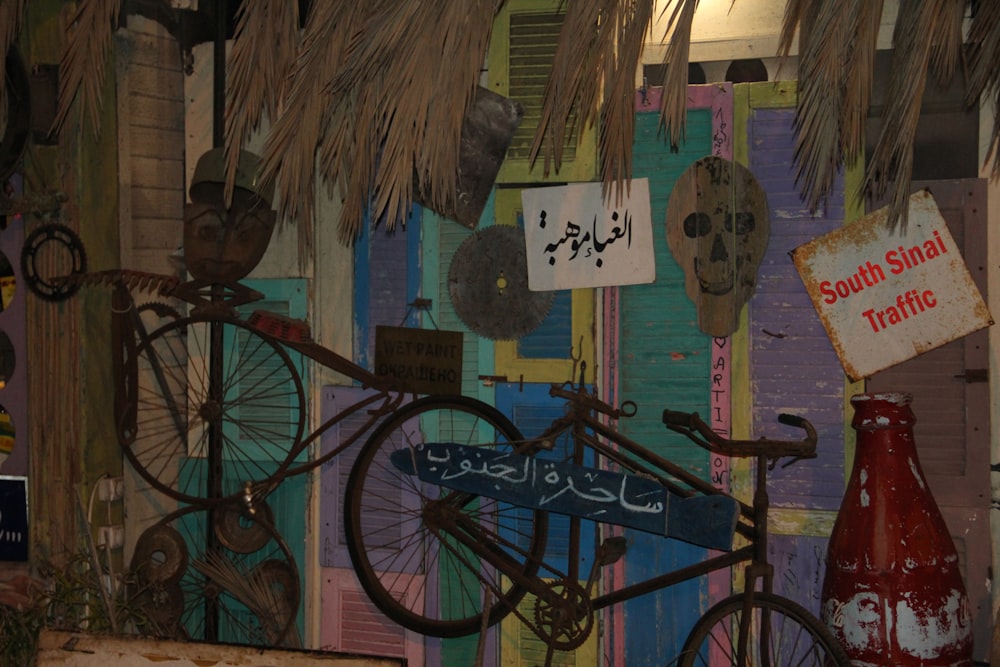 표지판으로 덮인 벽 옆에 주차된 자전거