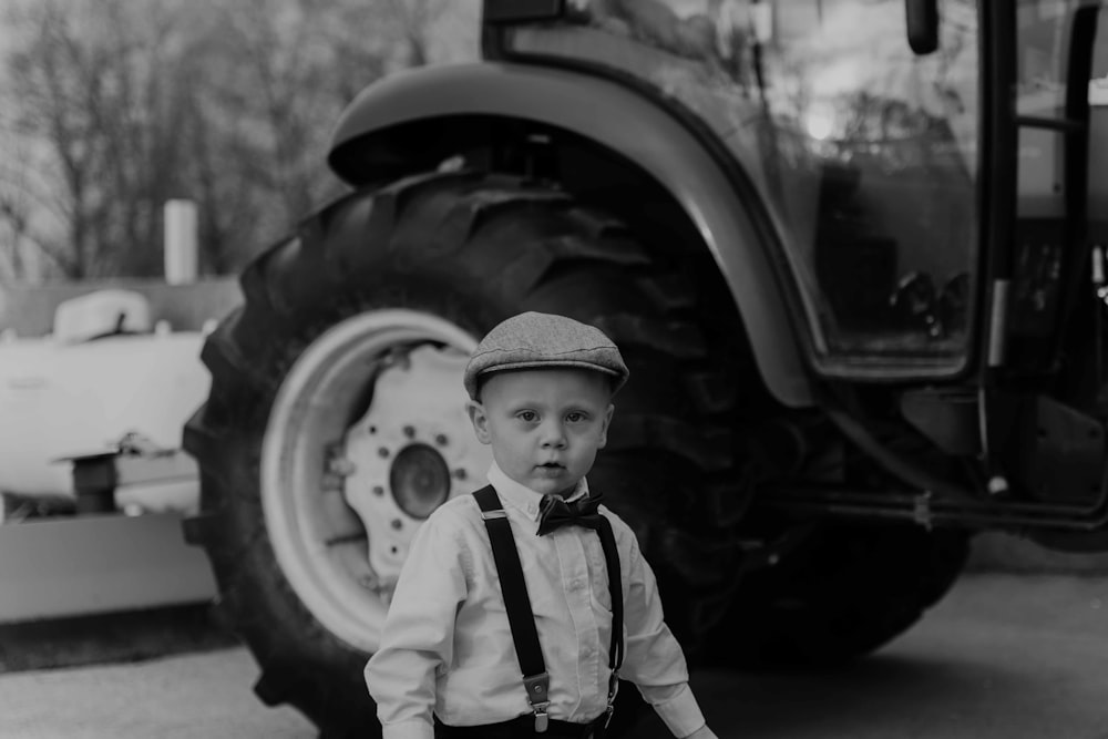 a young boy standing in front of a car