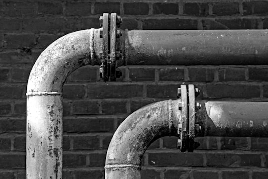 a black and white photo of pipes on a brick wall