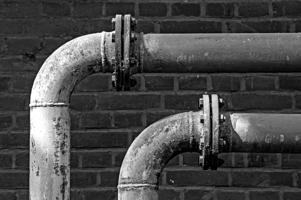 a black and white photo of pipes on a brick wall