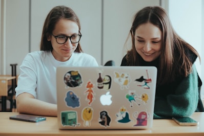 a couple of women sitting at a table with a laptop