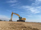 an excavator on a dirt field under a blue sky