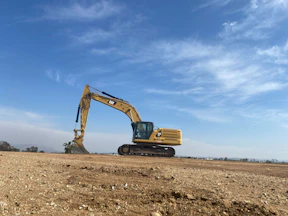an excavator on a dirt field under a blue sky