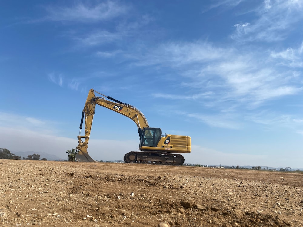 an excavator on a dirt field under a blue sky