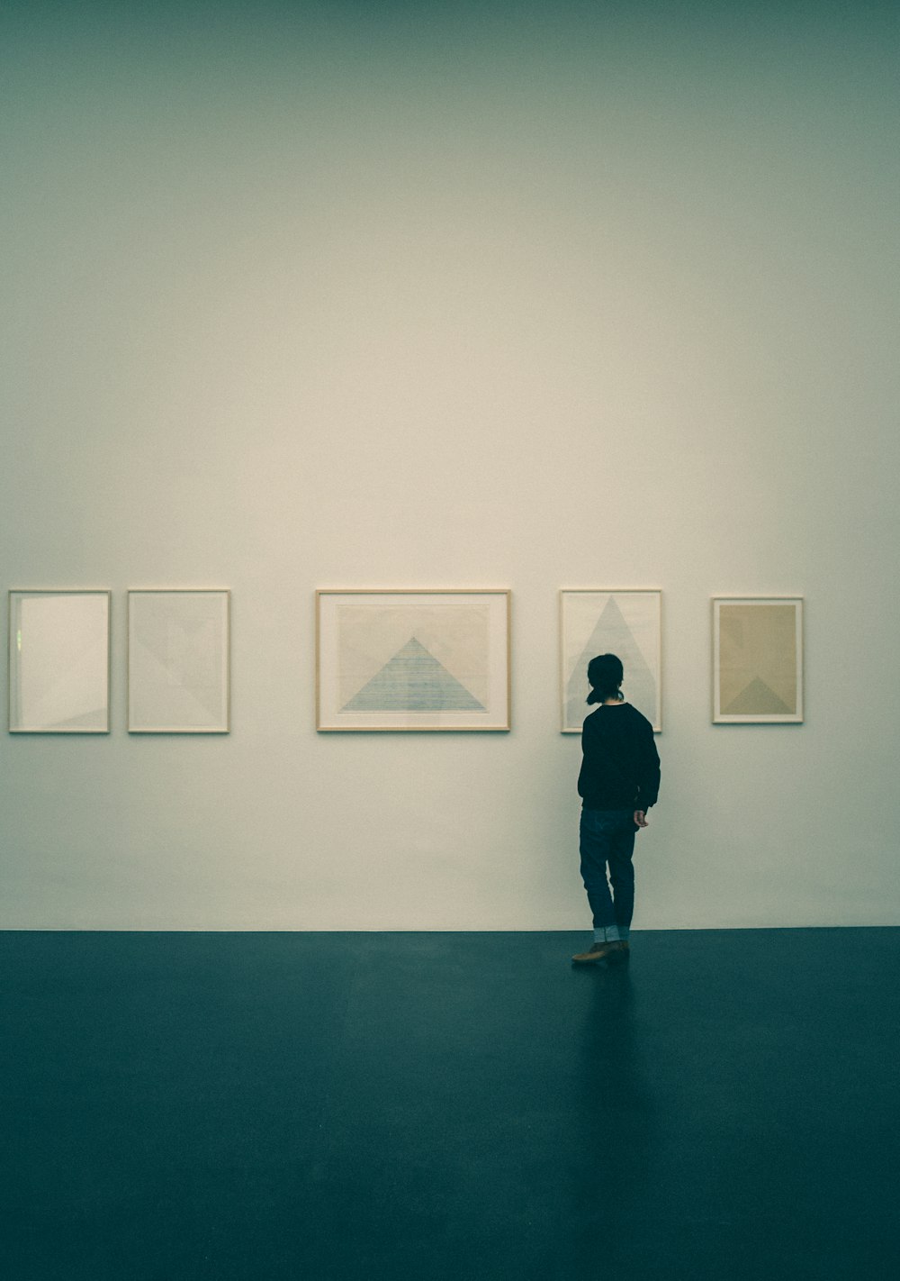 a person standing in front of a wall with paintings on it