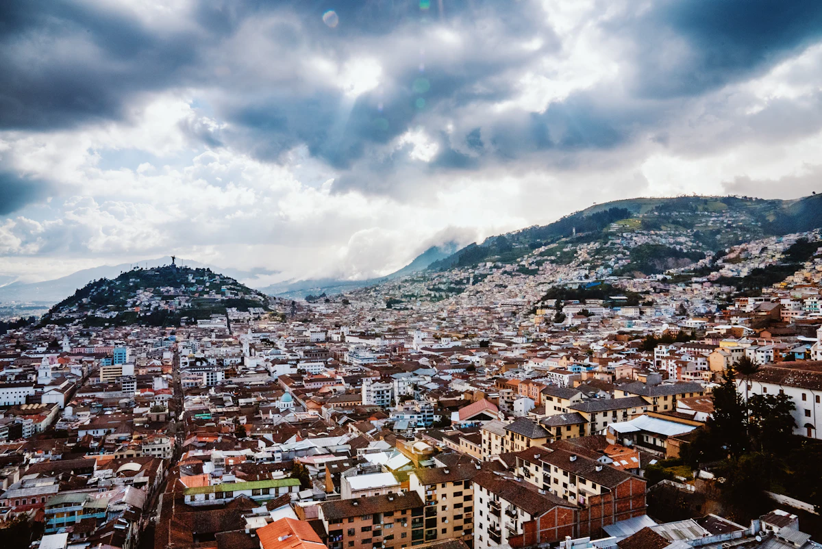 Quito's old town under heavy cloud, with a statue-topped hill on the left