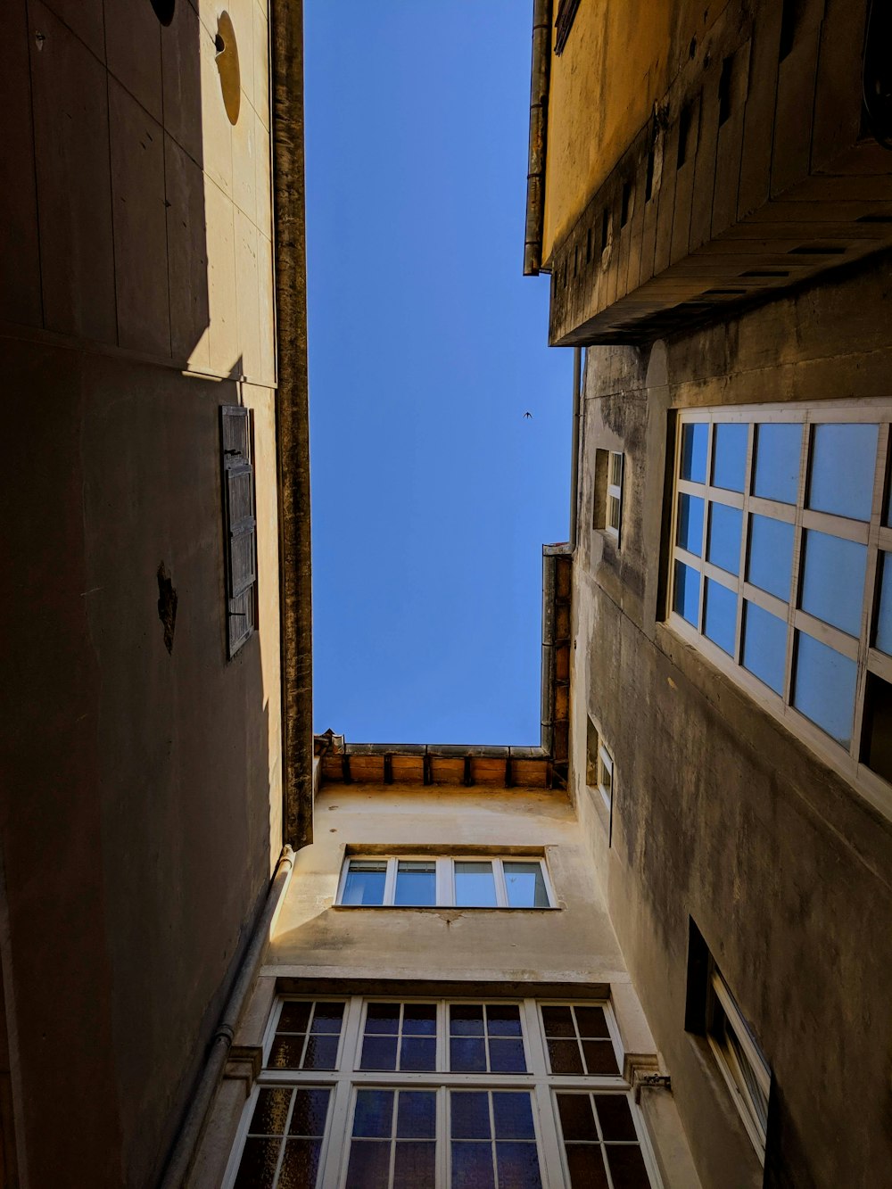 a narrow alley way with a window and sky in the background