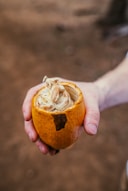 a person holding a peeled orange in their hand