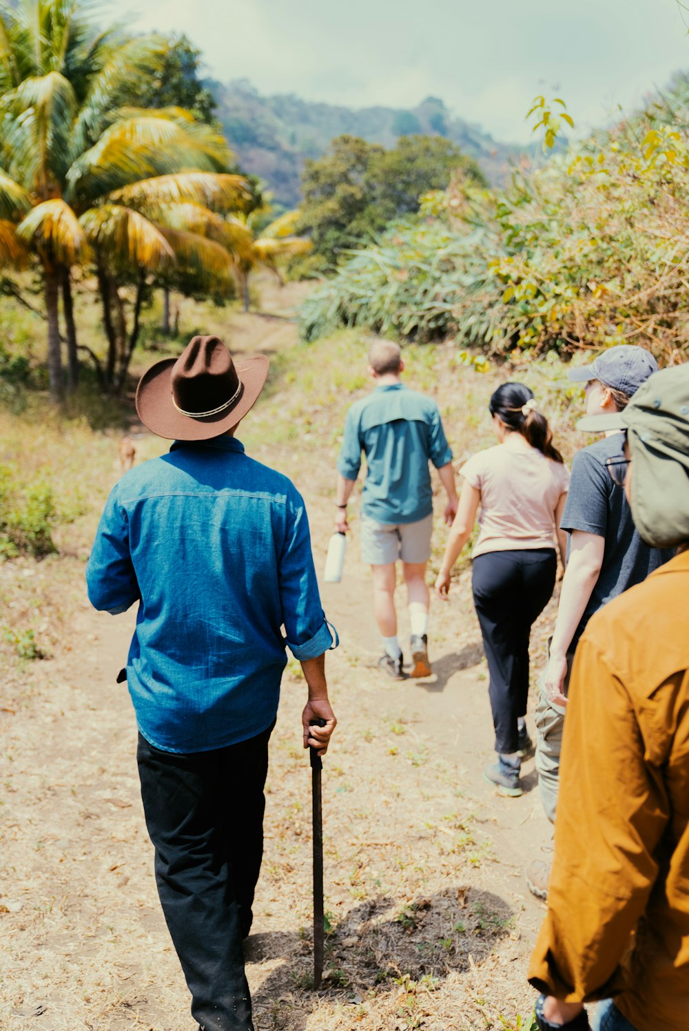 a group of people walking down a dirt road