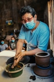 a man wearing a face mask is making pottery