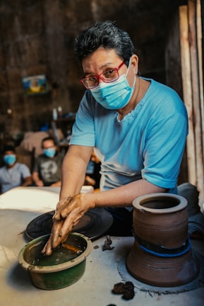 a man wearing a face mask is making pottery