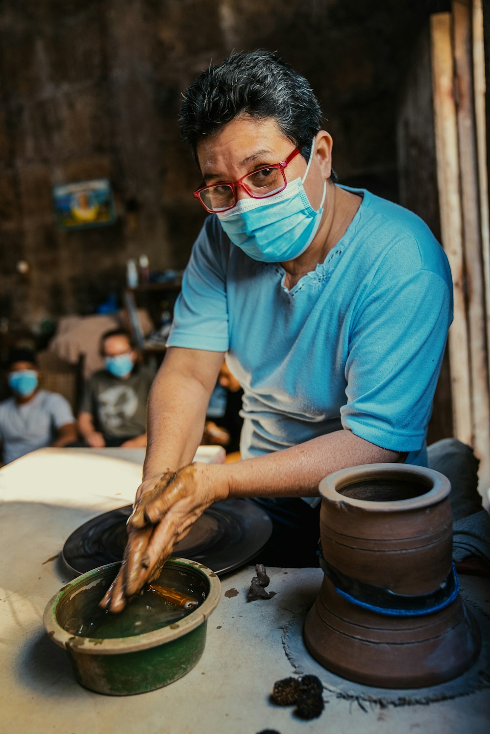 a man wearing a face mask is making pottery