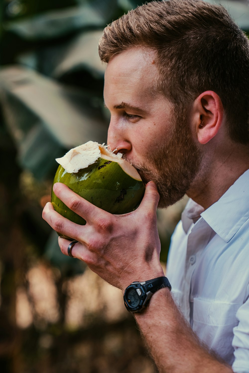 Un uomo in una camicia bianca che mangia una mela verde