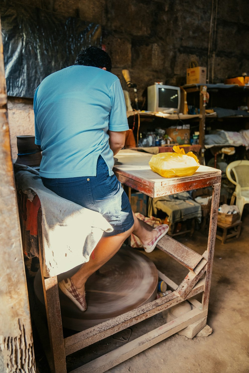 a man working on a pottery wheel in a workshop