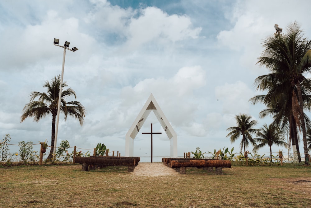a church with a cross and benches in front of it