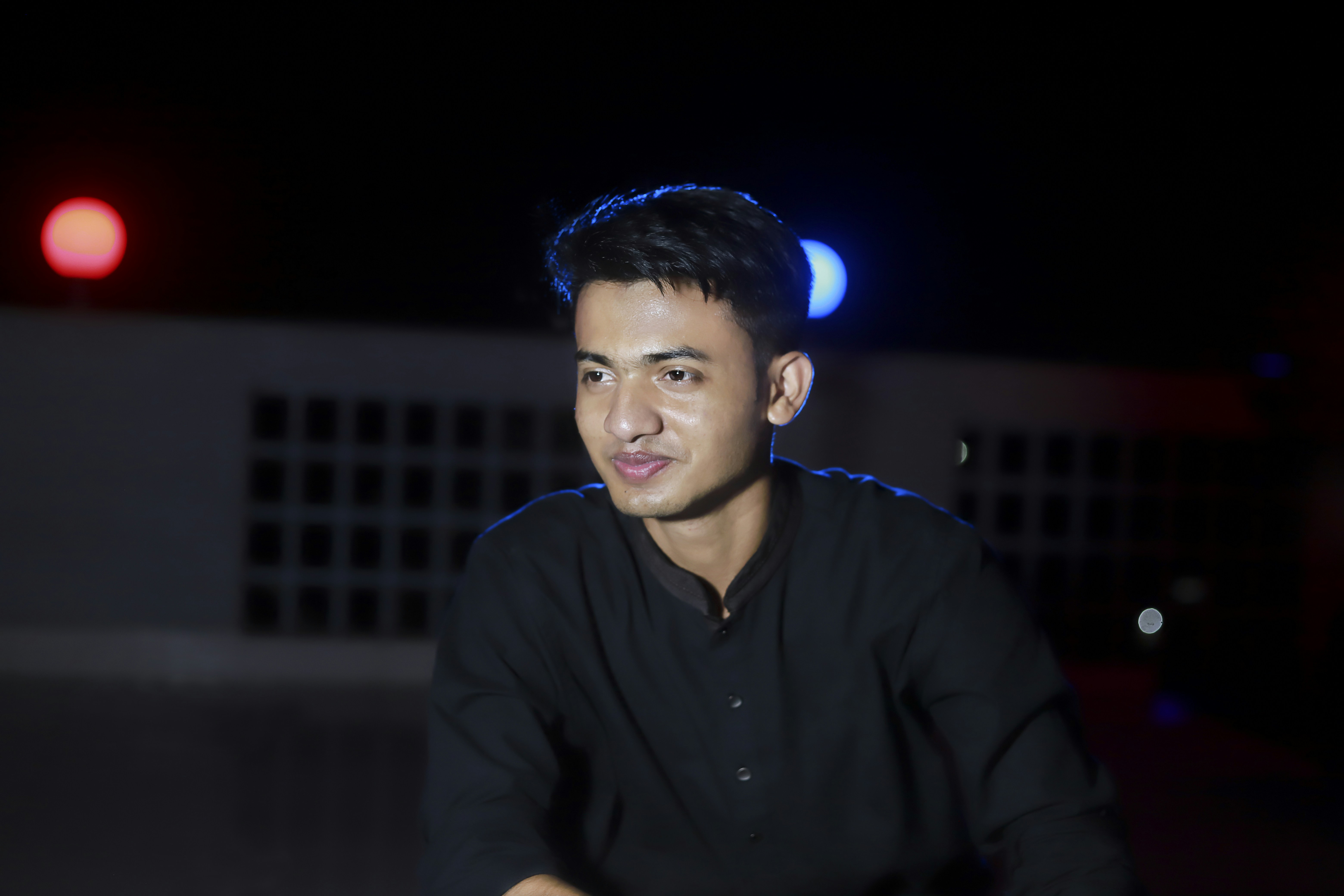 a man in a black shirt is sitting in the dark