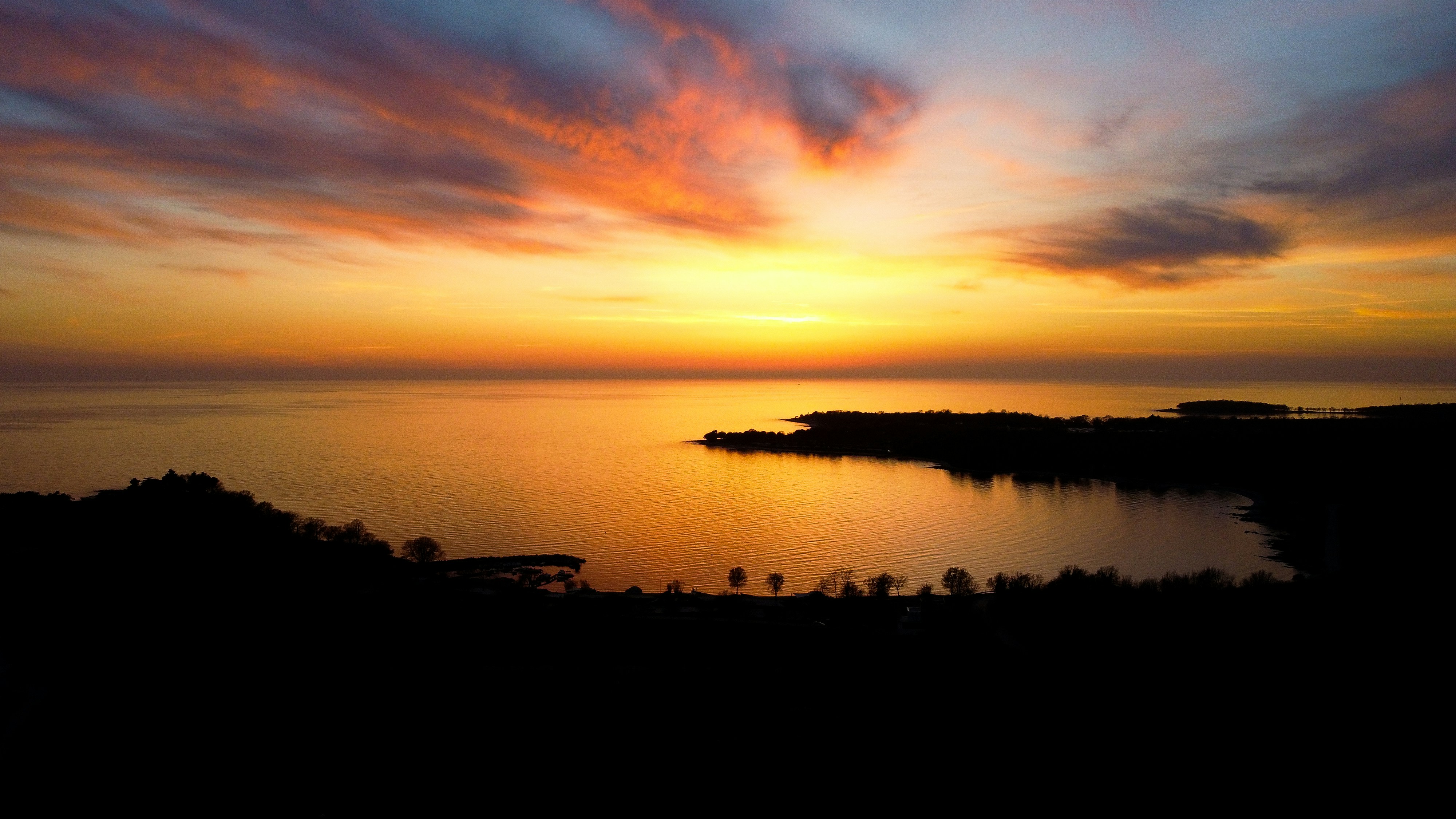 a sunset over a body of water with clouds in the sky
