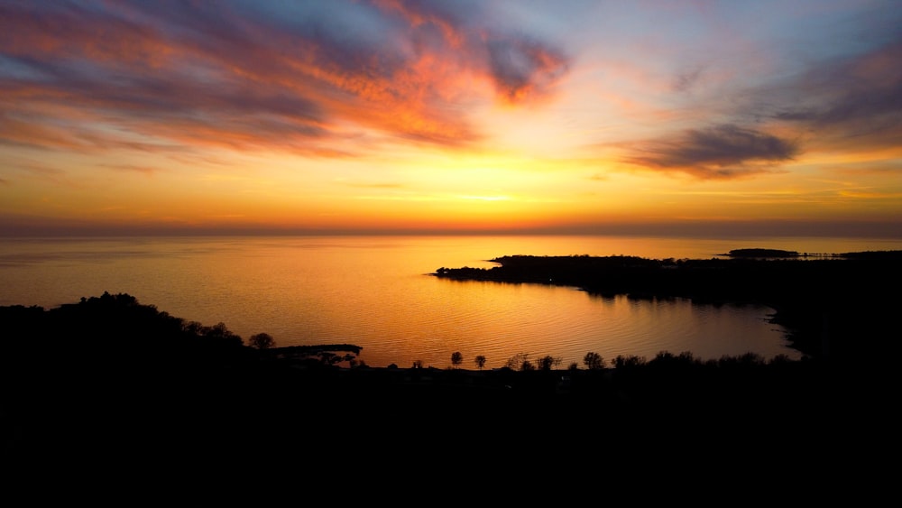 a sunset over a body of water with clouds in the sky