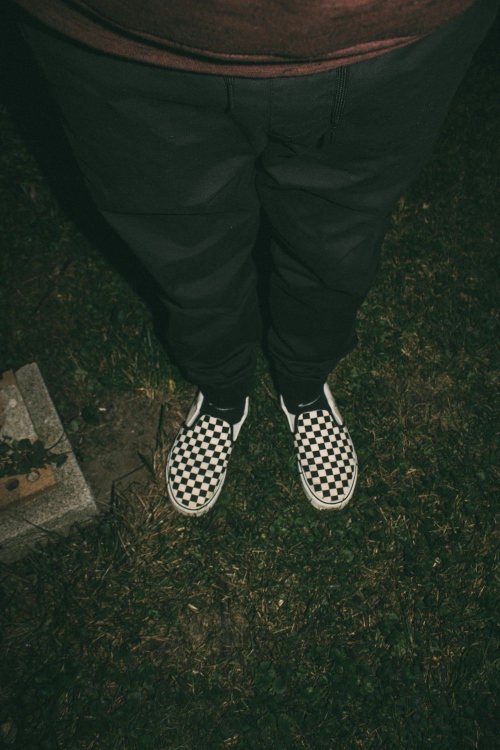 a person wearing checkered shoes standing in the grass