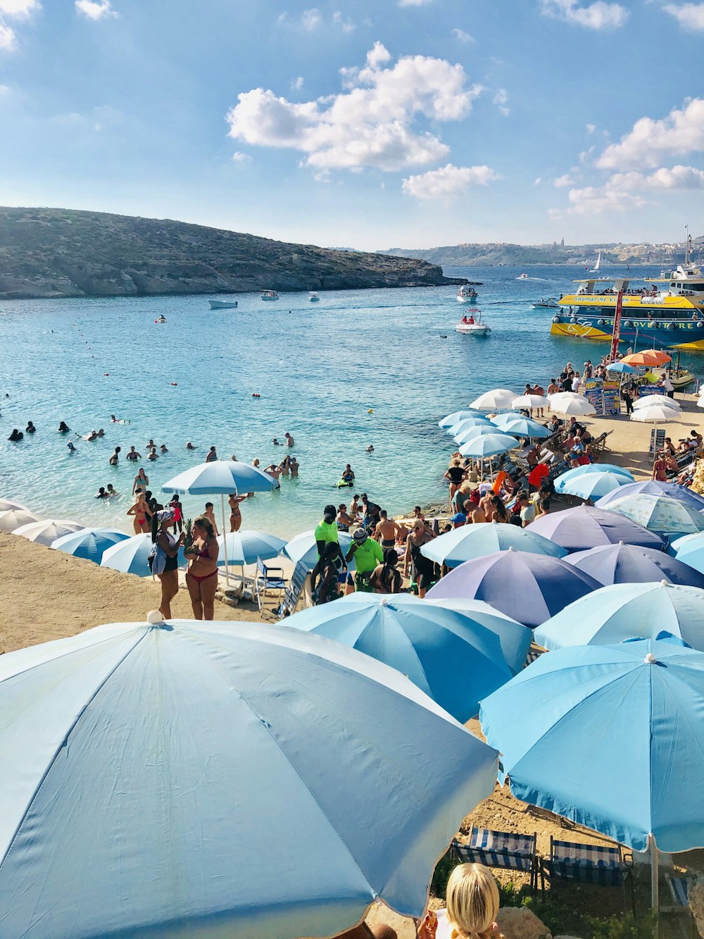 Une plage remplie de nombreux parasols bleus